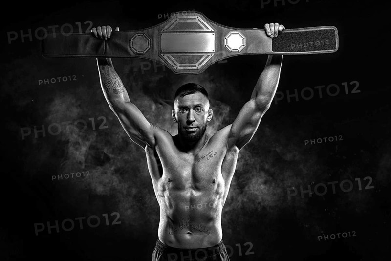 Kickboxer victoriously raises the belt won in the tournament against the backdrop of smoke. Sports competitions. Fight night. The concept of mixed martial arts. MMA