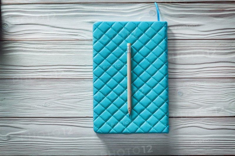 Blue leather soft notepad and classic wooden pencil on white vintage wooden boards