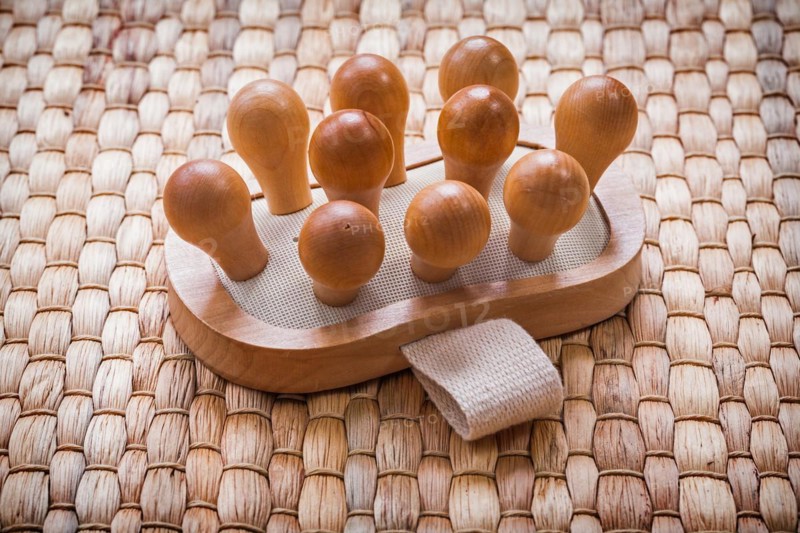Single wooden massager with rubber band on wicker mat Healthcare concept
