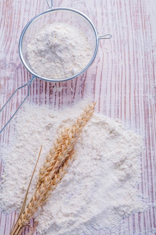 Ears of rice flour and sieve on an old wooden board