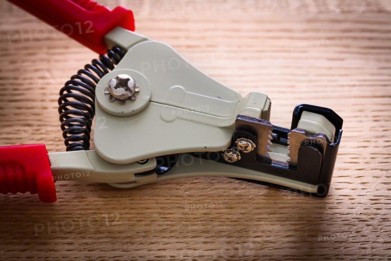 Close-up of an automatic wire stripper on a wooden board