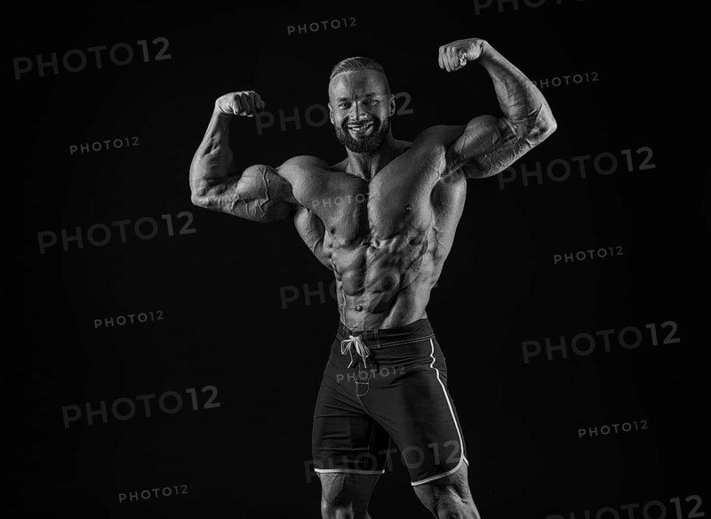 Silhouette of a strong bodybuilder. Confident young fitness athlete with a powerful body and perfect abs. Black and white photography. Dramatic light. Mixed media