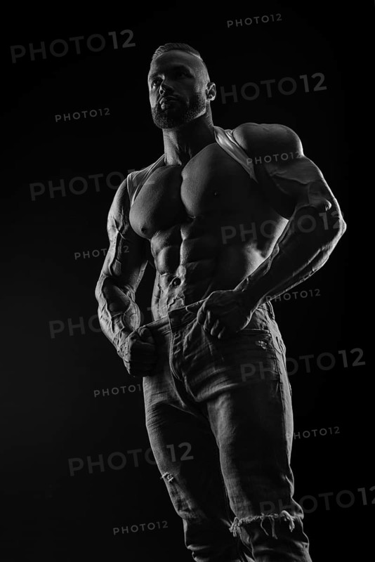 Silhouette of a strong bodybuilder. Confident young fitness athlete with a powerful body and perfect abs. Black and white photography. Dramatic light. Mixed media