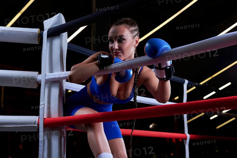 Beautiful and strong sportswoman posing in the corner of the ring. The concept of wrestling and boxing. Mixed media