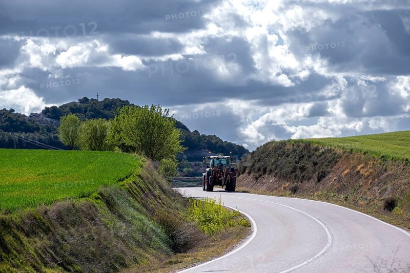 Tractor driving on a country road between crop fields in the province of Valladolid in Spain