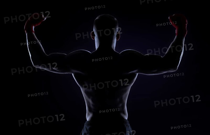 Kickboxer in red bandages raised his hands in victory. Back view. The concept of mixed martial arts. MMA