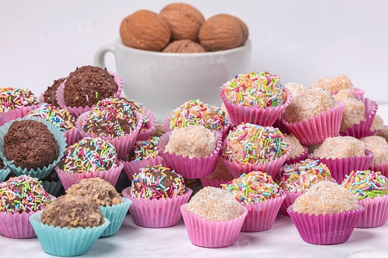 A selection of handmade light and dark rum balls on a white background