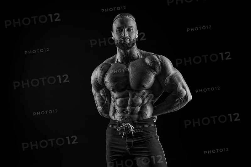 Silhouette of a strong bodybuilder. Confident young fitness athlete with a powerful body and perfect abs. Black and white photography. Dramatic light. Mixed media