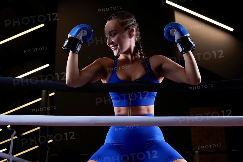 Beautiful and strong sportswoman posing on the ropes of the ring. The concept of wrestling and boxing. Mixed media