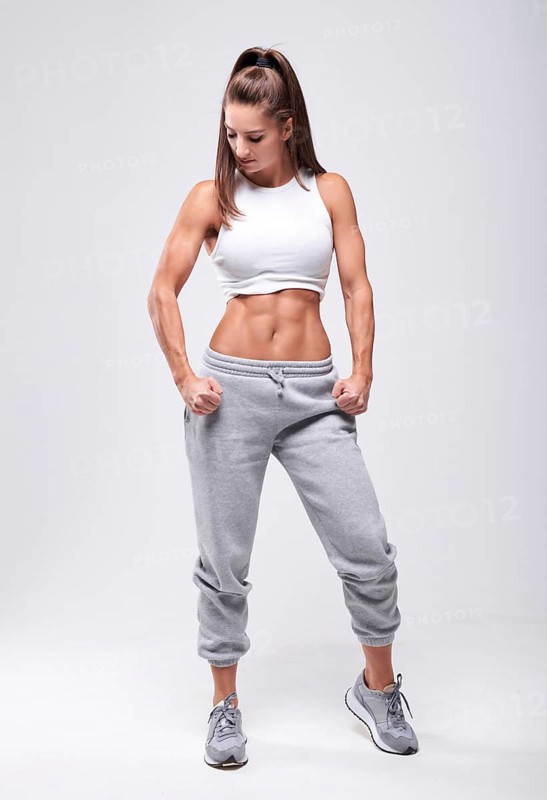 Young white fitness woman wearing sportswear standing over white wall background. Fitness concept. Mixed media
