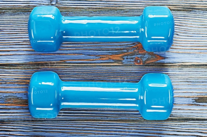Blue fitness dumbbells on vintage wooden board