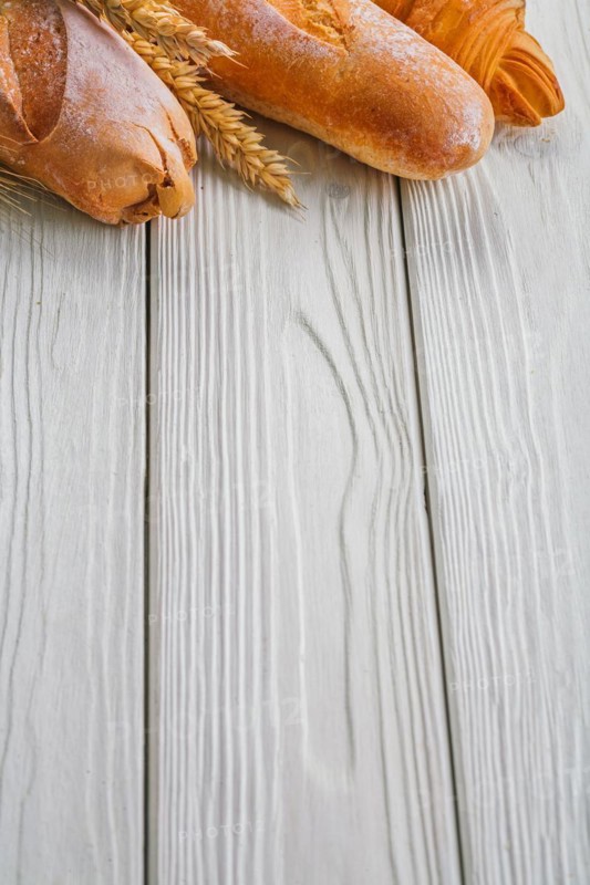 Copyspace image baguettes and ears of wheat rye on vintage wooden painted boards food and drink concept