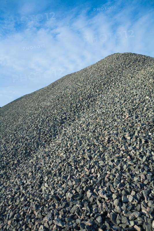 Close up view on big pile of grey gravel on background of blue sky