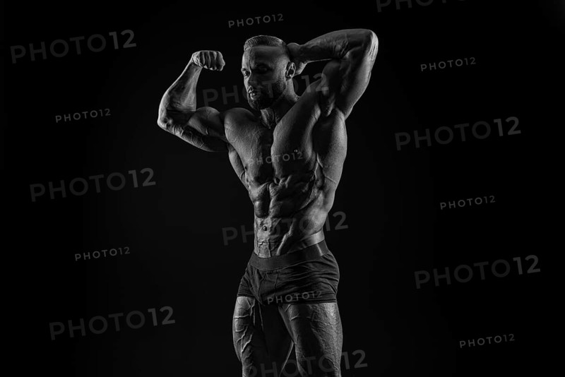 Silhouette of a strong bodybuilder. Confident young fitness athlete with a powerful body and perfect abs. Black and white photography. Dramatic light. Mixed media
