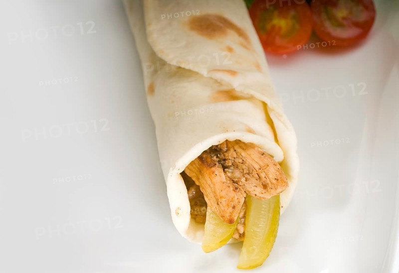 Pita bread chicken roll with pickles cucumbers on a plate with pachino tomatoes and lettuce