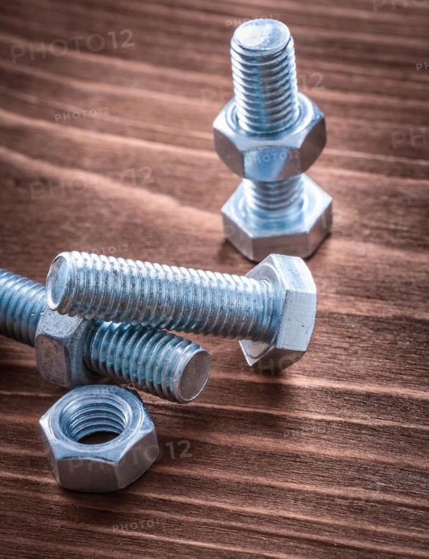 Group of stainless steel threaded bolts and nuts on vintage wooden board construction concept