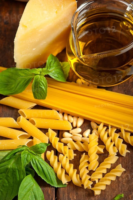 Italian basil pesto ingredients and raw pasta over old wood macro