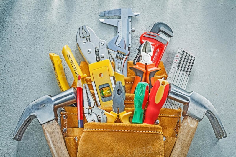 Composition of construction tooling in tool belt on concrete background