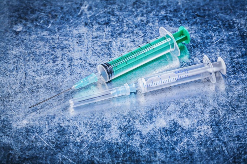 Medical disposable needle syringes on metallic background medicine concept