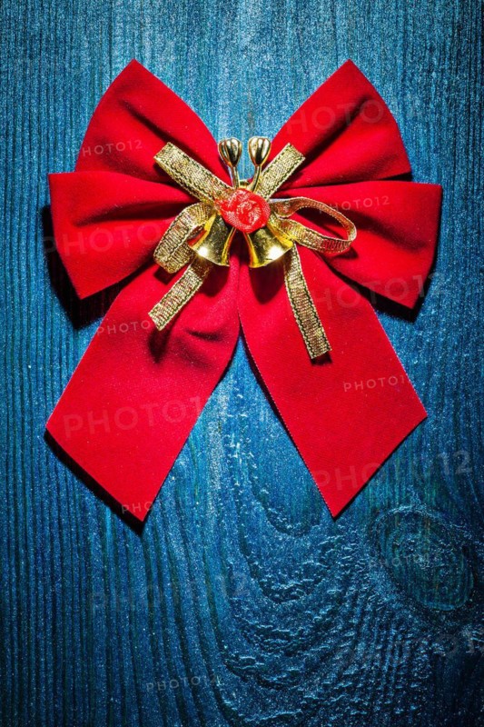 Beautiful red Christmas bow with gold ribbon and bells on an old blue lacquered wooden board