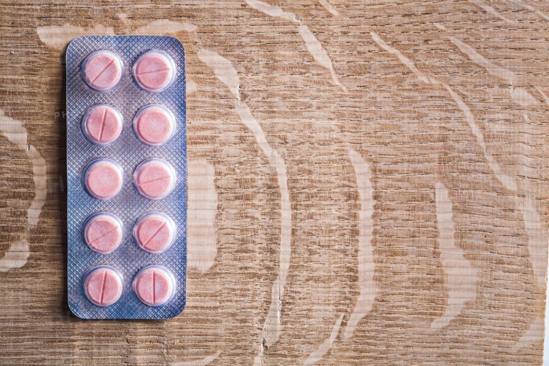 Blister pack with rose medical pils on wooden board with cpyspace