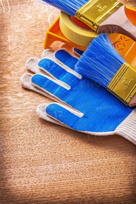 Paint tray Brushes Adhesive tape and protective gloves on wooden panel Construction concept