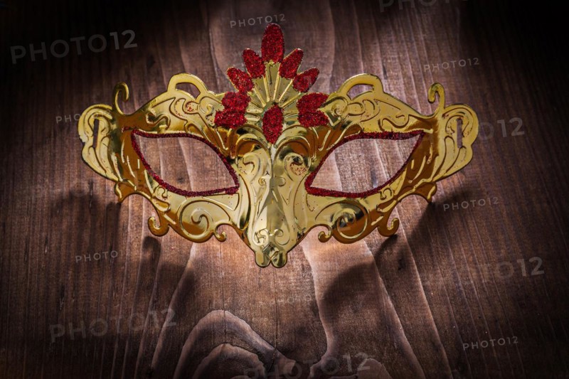 Gold-coloured carnival mask on an old wooden board