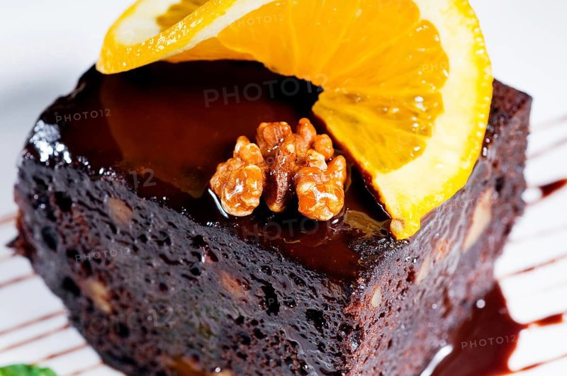 Fresh baked delicious chocolate and walnuts cake with slice of orance on top