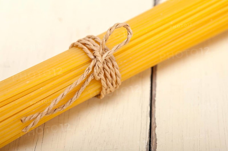 Italian pasta spaghetti tied with a rope on a rustic table