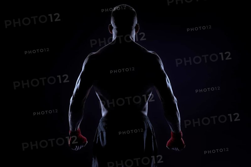 Kickboxer in red bandages posing on a blue background. Back view. The concept of mixed martial arts. MMA