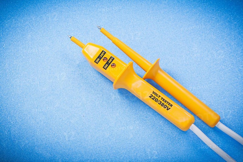 Yellow electrical tester isolated on blue surface electricity concept