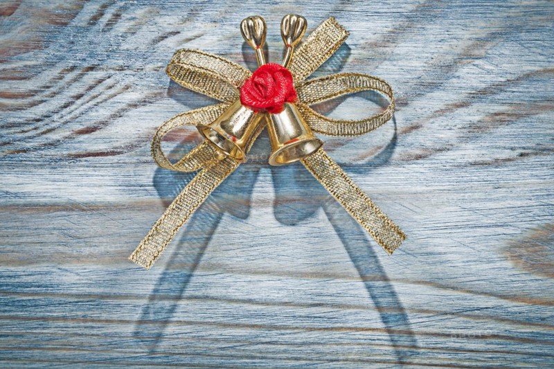 Golden Christmas knot with bell on wooden board holidays concept