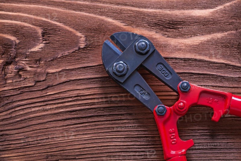 Black and red bolt cutters on wooden panel Construction concept