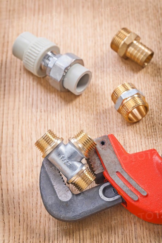 Plumbing accessories and spanners on wooden board