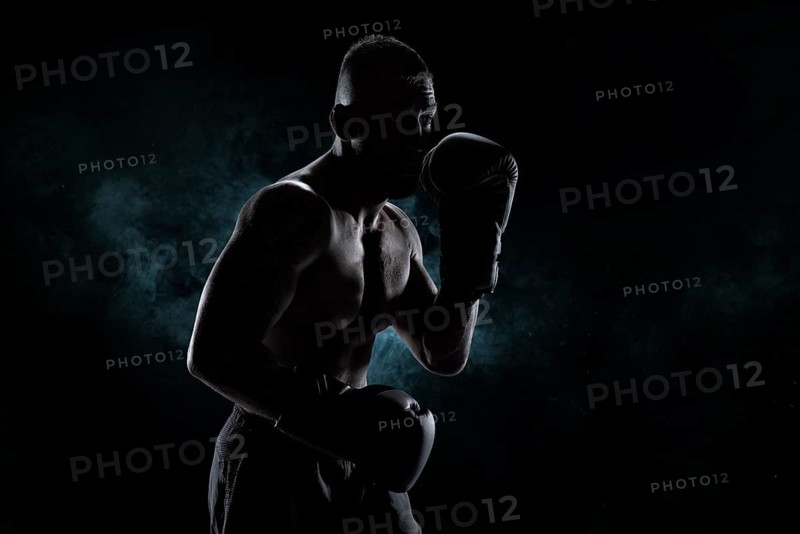 Kickboxer in black gloves posing on a background of smoke. The concept of mixed martial arts. MMA