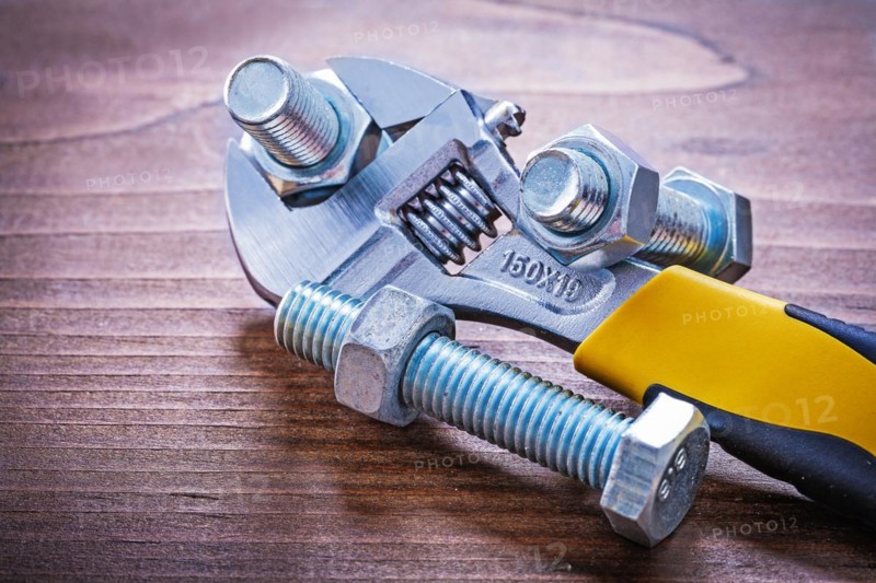 Adjustable spanner Steel threaded bolts and nuts on wooden plates Design concept
