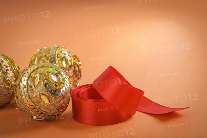 Golden Christmas baubles and red bow on a brown background