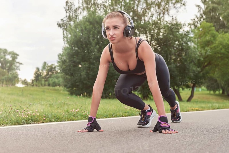 Image of a girl in headphones who stands in a lower position before starting to run. The concept of a healthy lifestyle. Mixed media