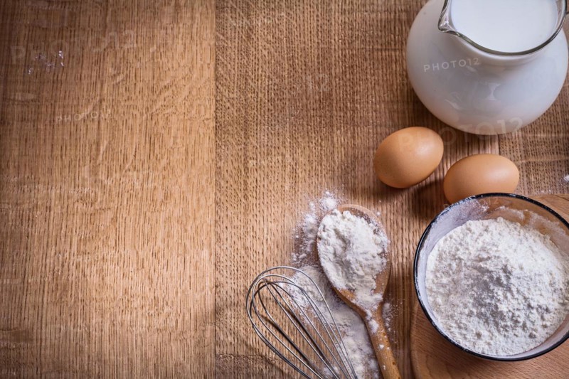 Organised copyspace flour in bowl and spoon corolla egss pitcher with milk on wooden board food and drink still life