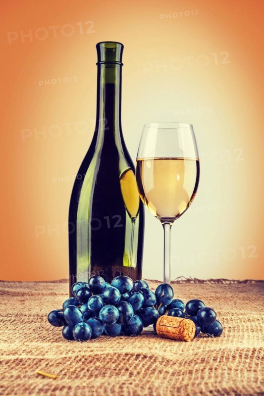 Bottle of wine and wineglass with branch of grape on burlap instagram style