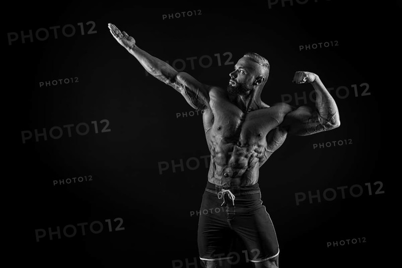 Silhouette of a strong bodybuilder. Confident young fitness athlete with a powerful body and perfect abs. Black and white photography. Dramatic light. Mixed media