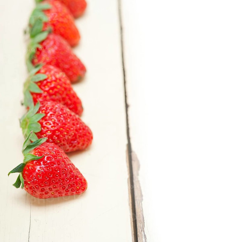 Fresh organic strawberry over white rustic wood table