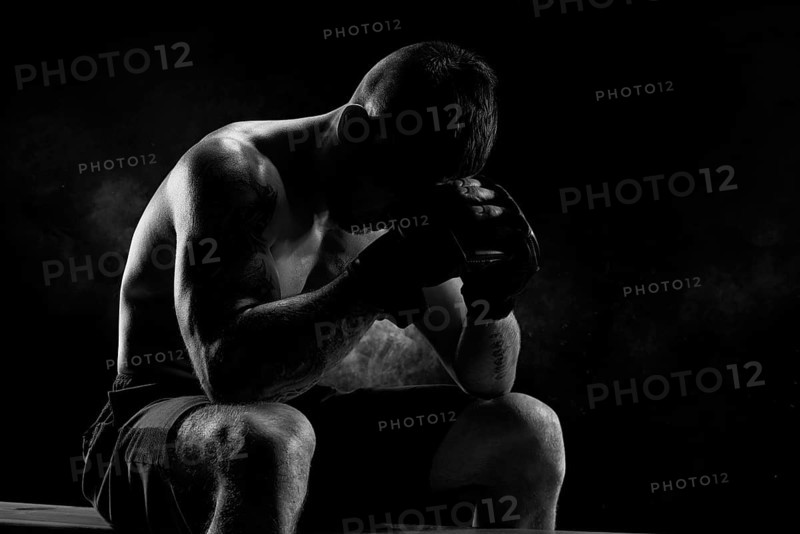 Kickboxer with overlays on his hands prays before the fight. The concept of mixed martial arts. MMA