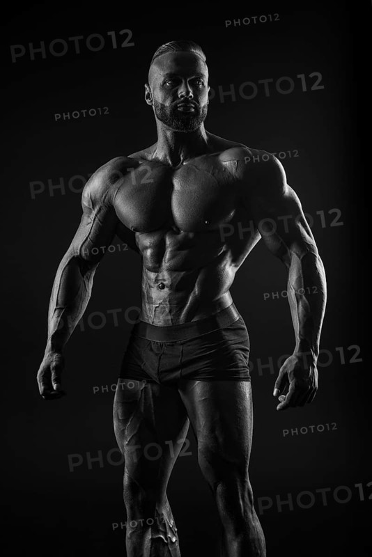 Silhouette of a strong bodybuilder. Confident young fitness athlete with a powerful body and perfect abs. Black and white photography. Dramatic light. Mixed media