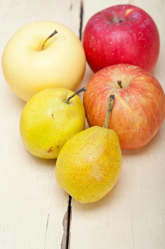 Fresh fruits apples and pears on a white wood table