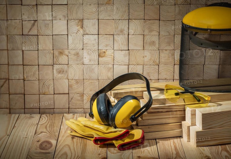 Carpenter tools headphones gloves goggles and saw mask on wooden background