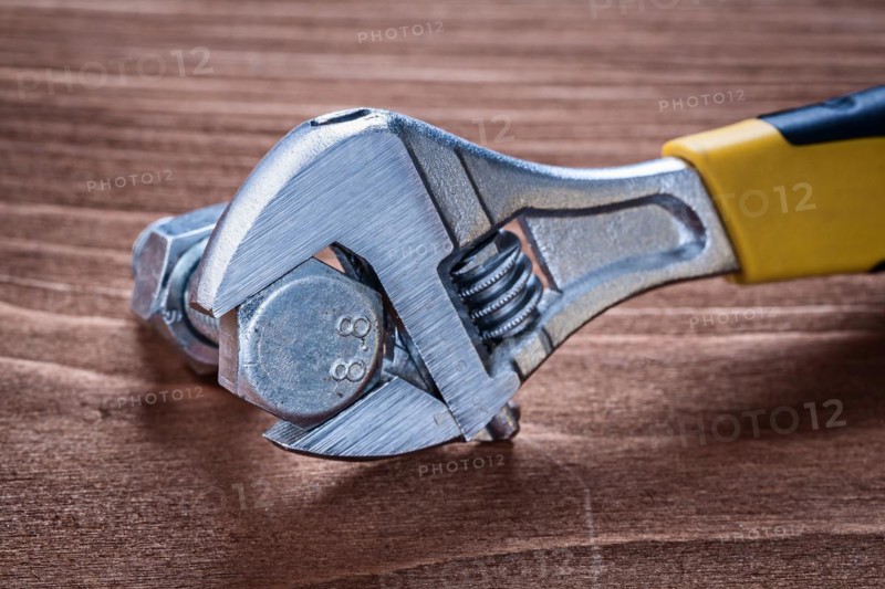 Adjustable spanner stainless bolt and screw nut on brown wooden board construction concept