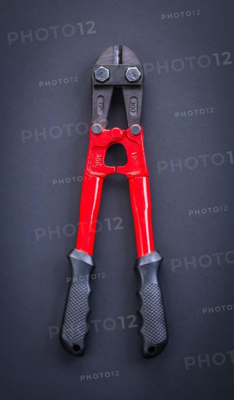 Aerial view of a red steel cutter with rubber handle on a black background