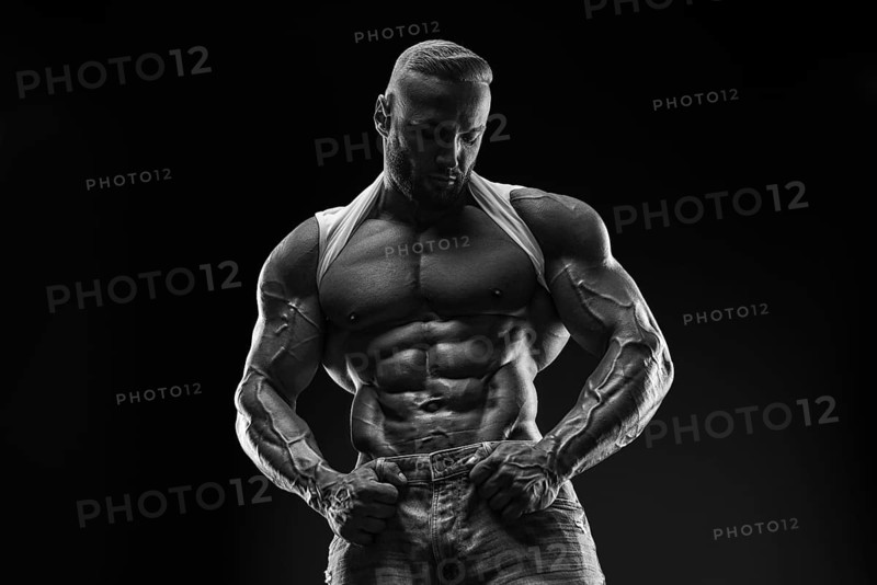 Silhouette of a strong bodybuilder. Confident young fitness athlete with a powerful body and perfect abs. Black and white photography. Dramatic light. Mixed media