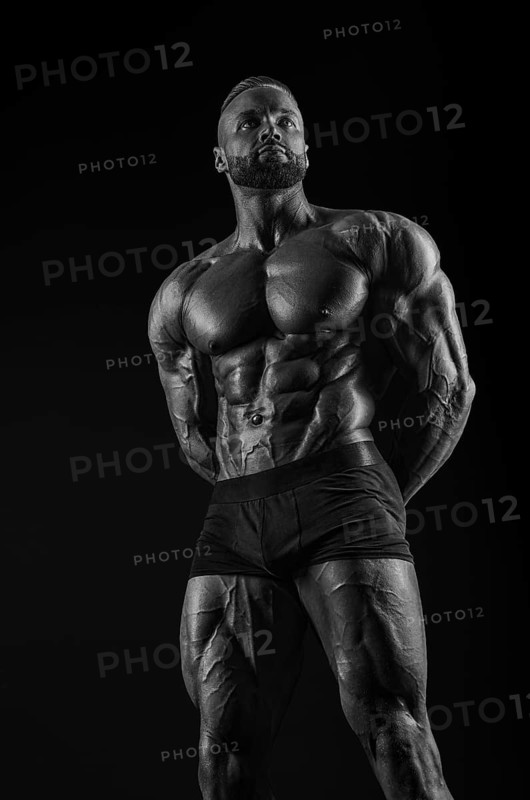 Silhouette of a strong bodybuilder. Confident young fitness athlete with a powerful body and perfect abs. Black and white photography. Dramatic light. Mixed media